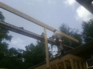 Carpenter setting a ridge beam over a new addition frame — Ice Dam Removal by Roofing Brothers in Forest City