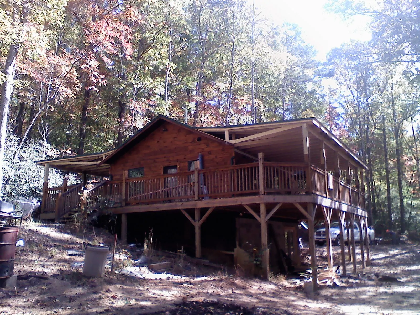 Log cabin with a wraparound porch and metal roof in the fall in Forest City
